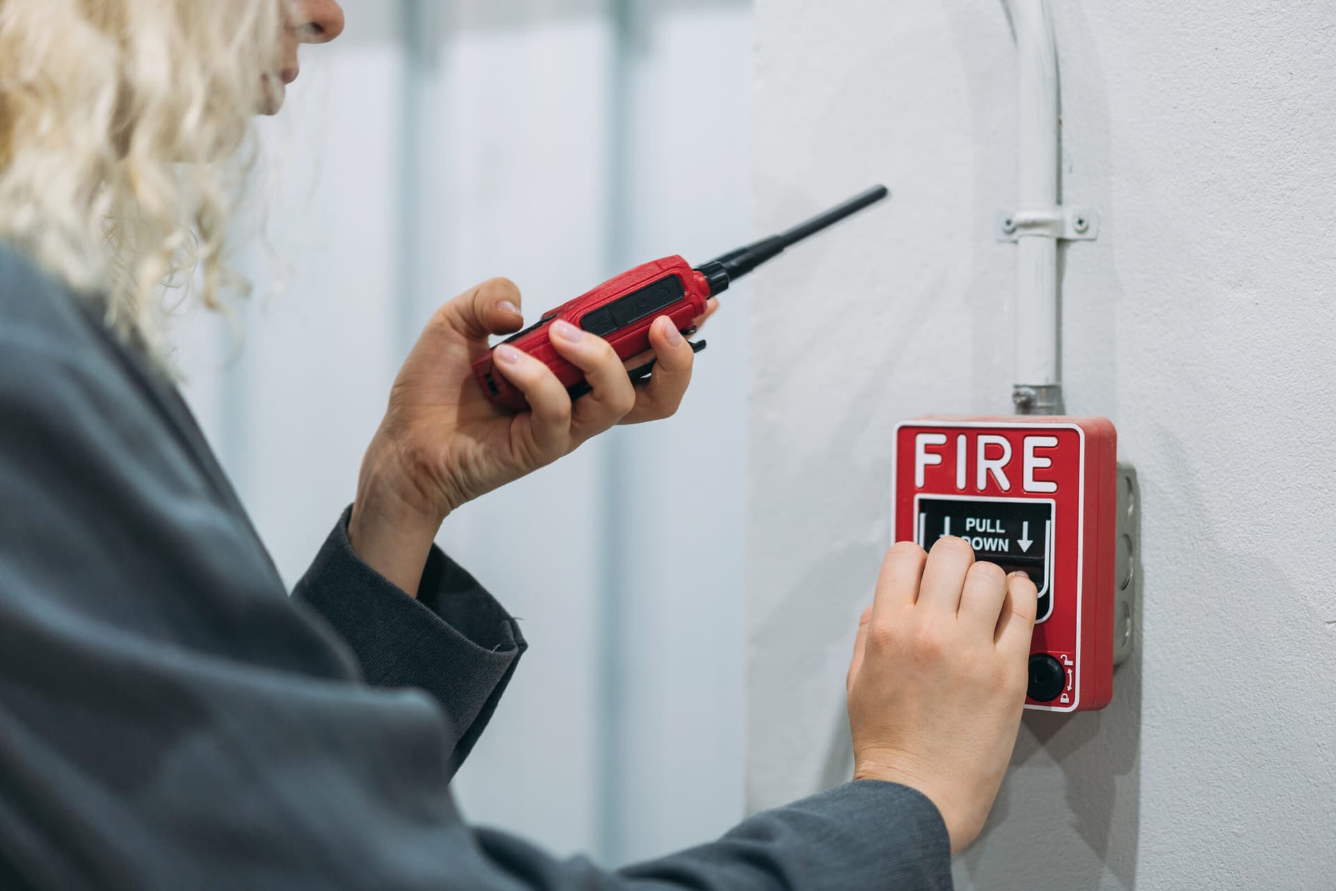 Technician activating a fire alarm pull station while using a walkie-talkie