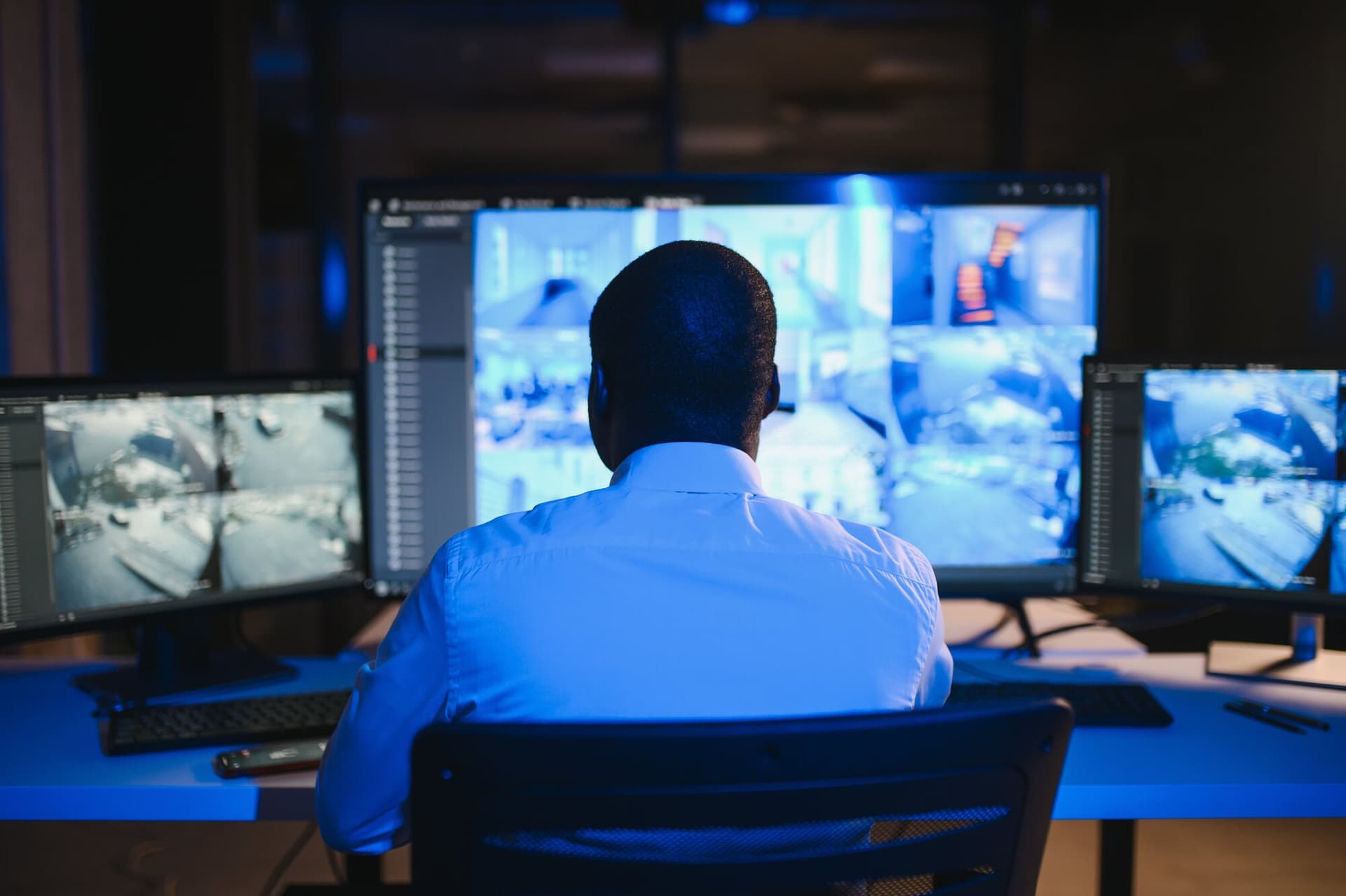 Security operator monitoring multiple live surveillance camera feeds in a control room