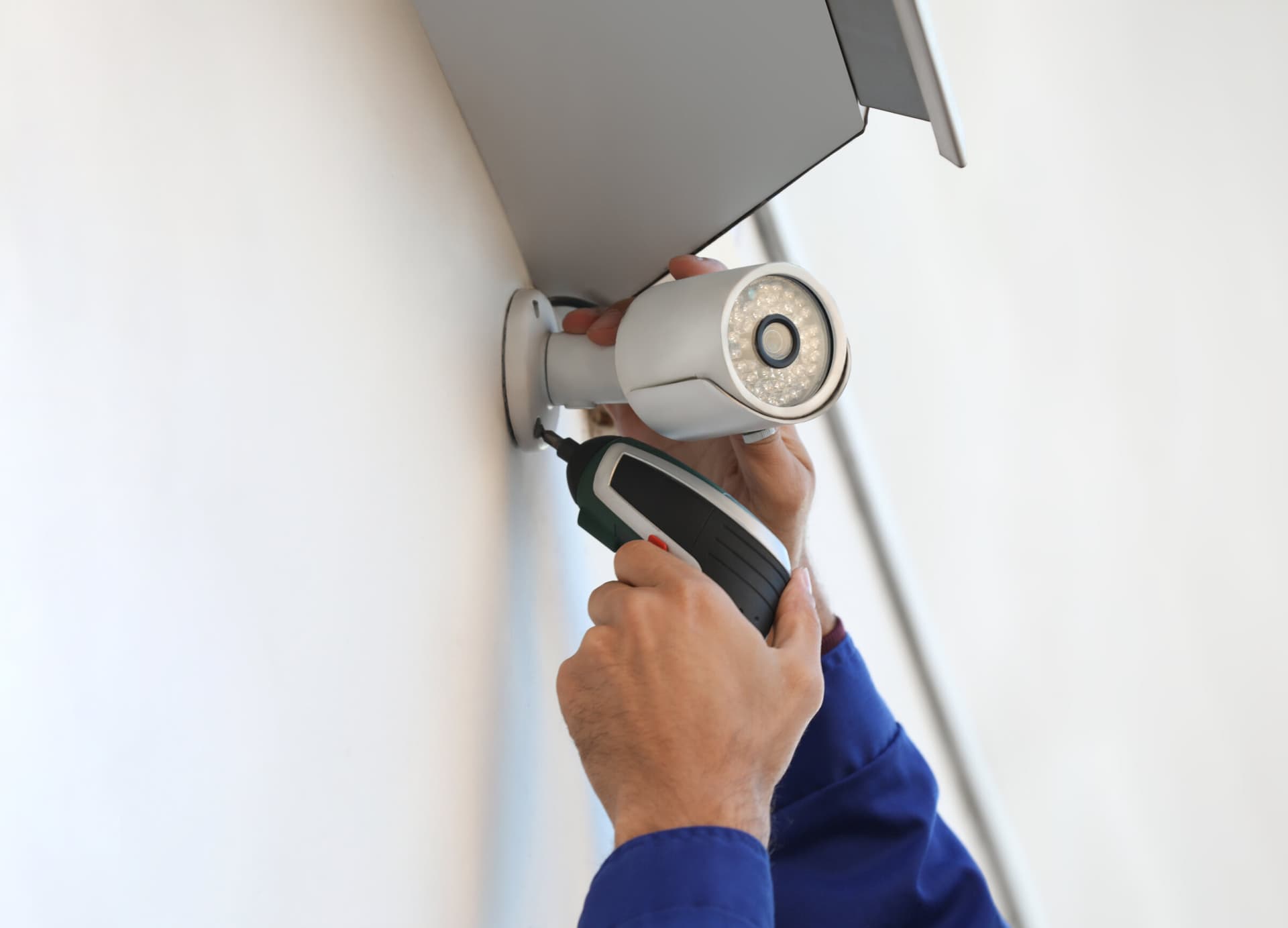 Technician securing a security camera to an indoor wall