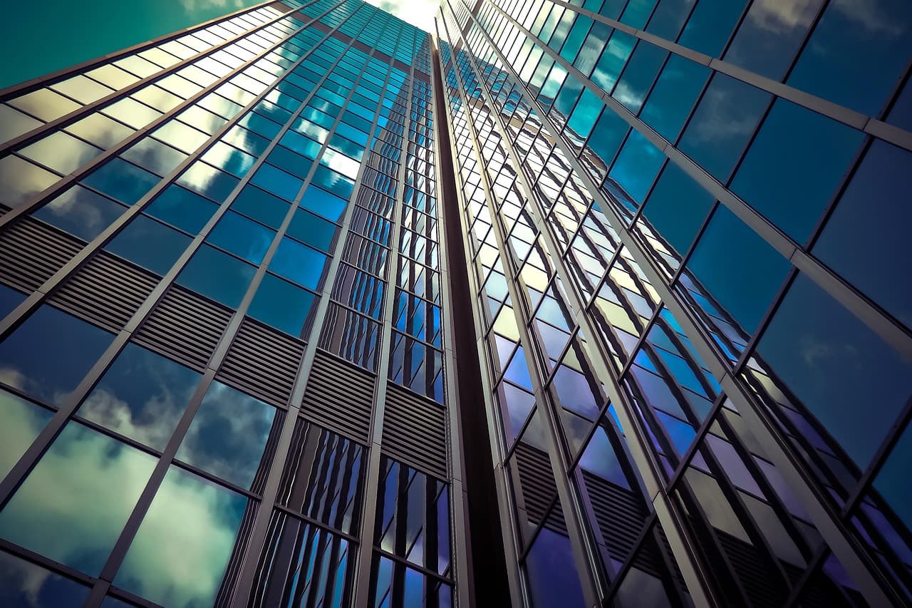 Modern glass-facade commercial office tower reflecting a blue sky
